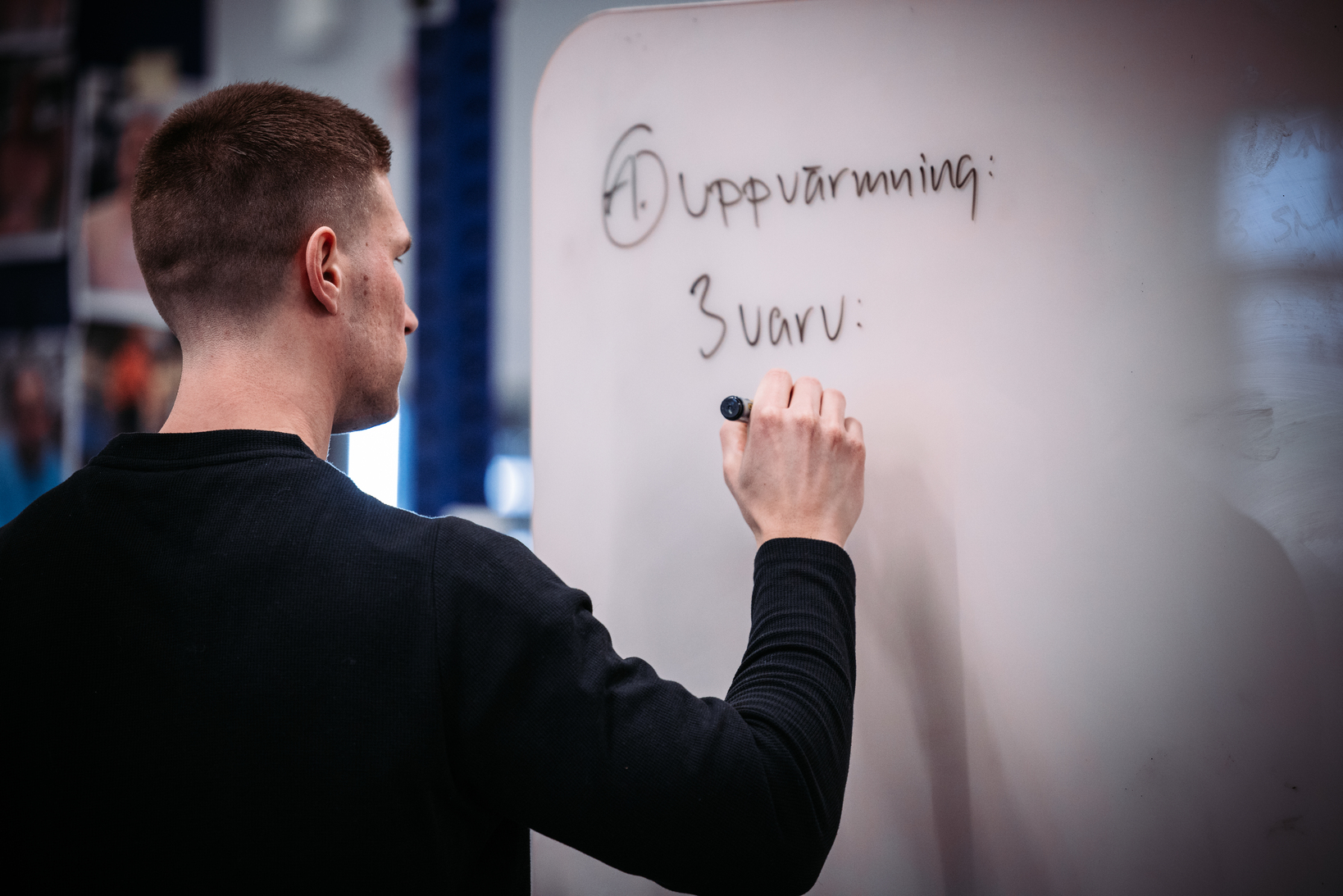 Linus skriver workout of the day pa whiteboard.